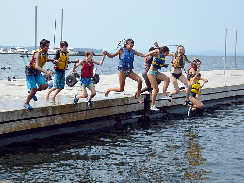 Youth campers jumping off dock